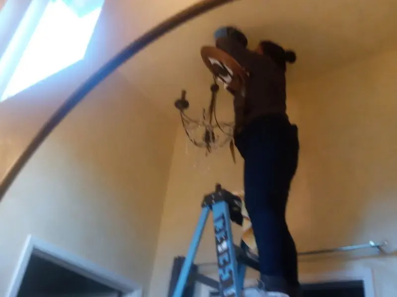 Electrician installing a chandelier in a Smithtown residence